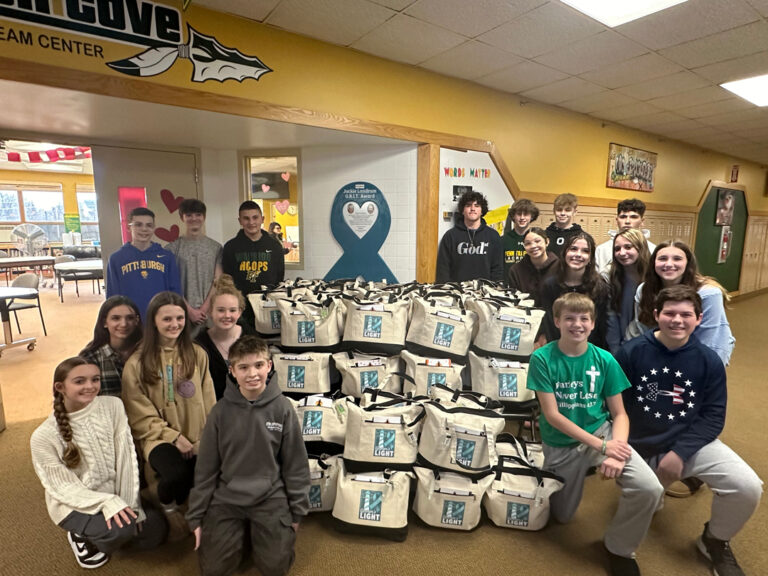 The group of Penn-Trafford students around a pile of tote bags they packed for the UPMC Hillman Cancer Center patients.